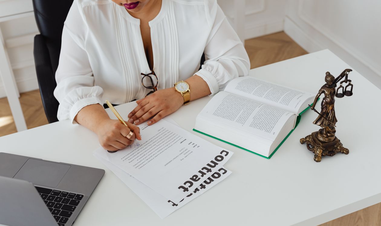 Attorney writing a legal memorandum at a desk surrounded by law books